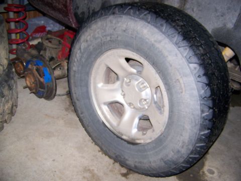 2001 Dodge 1500 - Disassembled vehicle parts, including a wheel, tire, coil spring, and brake assembly, are visible in this close-up shot.
