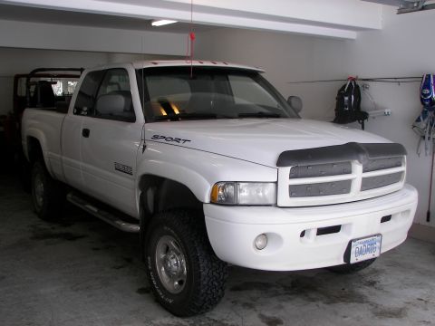 1990 Chevrolet Suburban - This white Dodge Ram pickup truck is parked inside a garage.