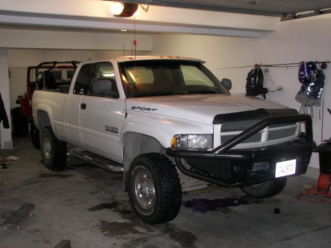 1990 Chevrolet Suburban - This white Dodge Ram pickup truck is parked in a garage, with a red Jeep in the background.