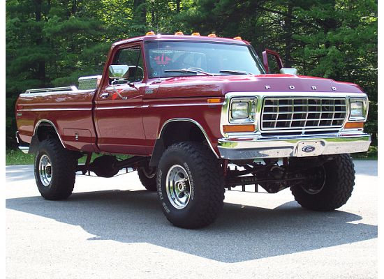 Red 1978 Ford F-150 lifted pickup truck parked on asphalt with trees in background