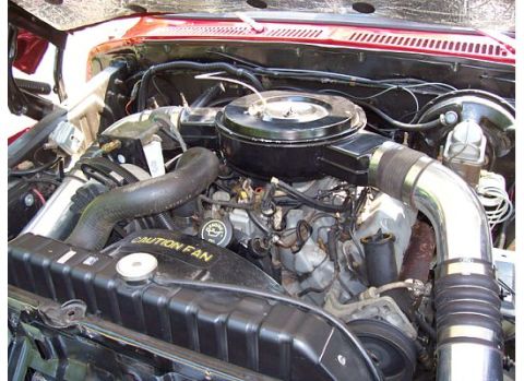 1978 Ford F-150 - The engine bay of a 1978 Ford F-150, its V8 engine and a prominent chrome intake pipe.