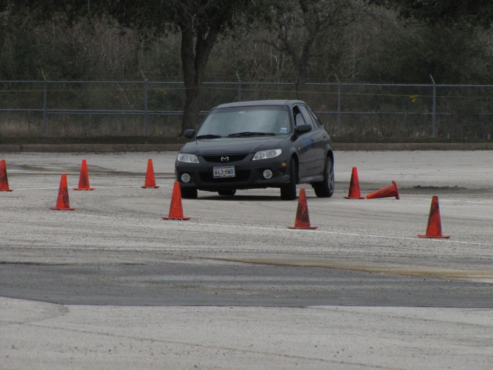 2003 Mazda Protege driving through an autocross course with orange cones