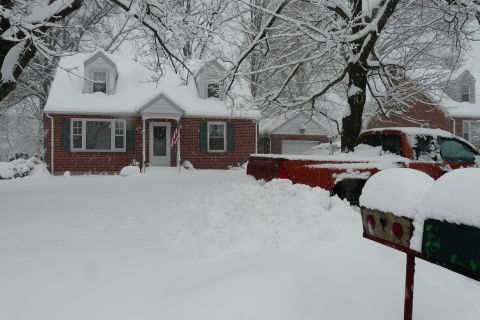 2000 Dodge Dakota - A red pickup truck is covered in snow in front of a house during a winter storm.