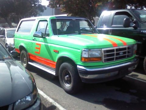 1994 Ford Bronco - This 1994 Ford Bronco sports a vibrant green paint job with contrasting orange stripes and a prominent number '3' on its side.