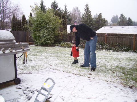 1991 Ford Bronco - A man and a child stand in a snowy backyard next to a grill.