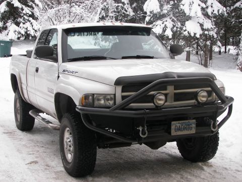 1990 Chevrolet Suburban - This white pickup truck, likely a 1994 model, is equipped with a heavy-duty brush guard and is parked in a snowy environment.