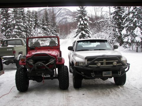 1990 Chevrolet Suburban - Two off-road vehicles, a Toyota Land Cruiser and a Dodge Ram, are parked outside in a snowy landscape.
