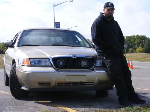2000 Mercury Grand Marquis - A man poses with a gold sedan, which appears to be a 2000 Mercury Grand Marquis.