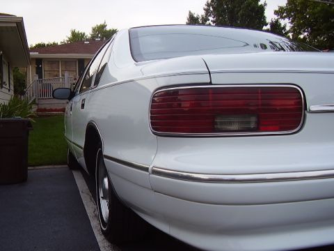 1996 Ford F-150 - White sedan's rear end with chrome trim and horizontal taillight detail.