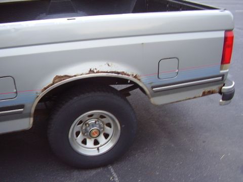 1996 Ford F-150 - Rear view of a silver 1996 Ford F-150 pickup truck showing rust damage.