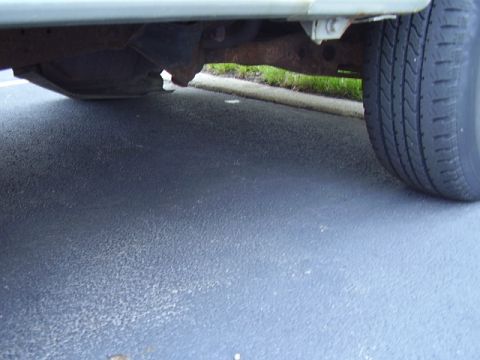 1996 Ford F-150 - The underside of a vehicle is visible, with a tire on the right and rusty frame components.