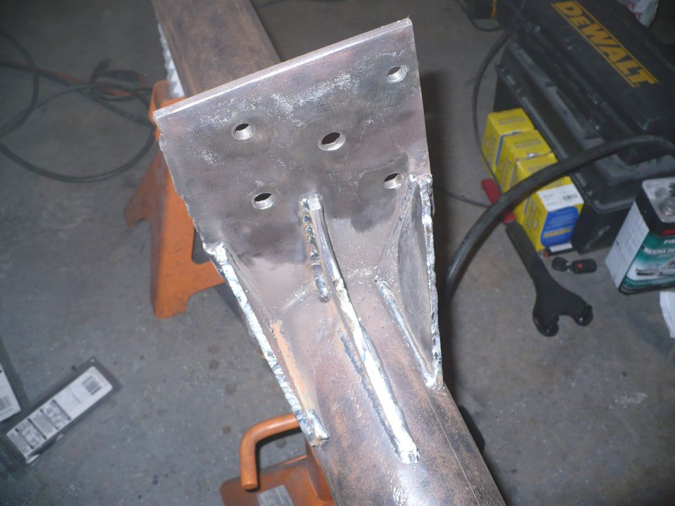 Metal bracket welded to a pipe, supported by an orange jack stand