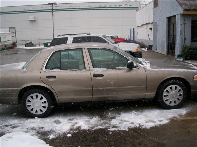 2006 Ford Crown Victoria parked in snow, side view. Another SUV and truck are visible behind it
