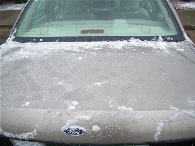 Car hood and windshield covered in snow. Ford logo visible on hood