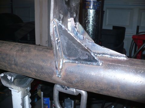 1979 Ford Bronco - Close-up view of welded metal brackets attached to a pipe, likely a component of a vehicle's frame or suspension system.