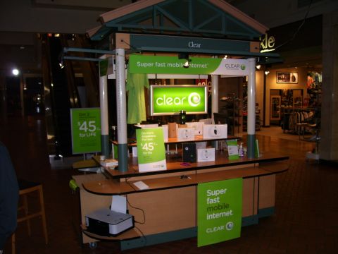 1991 Ford Bronco - A retail kiosk for Clear mobile internet services is set up inside a shopping mall, promotional signage and product displays.