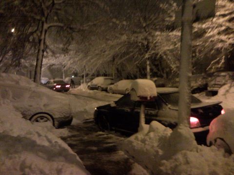 2007 Subaru Impreza - A winter storm blankets parked cars and trees on a street at night.