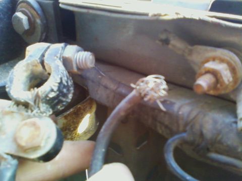 1990 Ford Bronco - Close-up of a corroded battery terminal and a frayed wire, likely from a vehicle's engine bay.