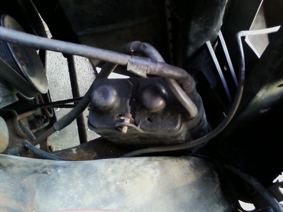 Close-up of a black engine part with hoses attached