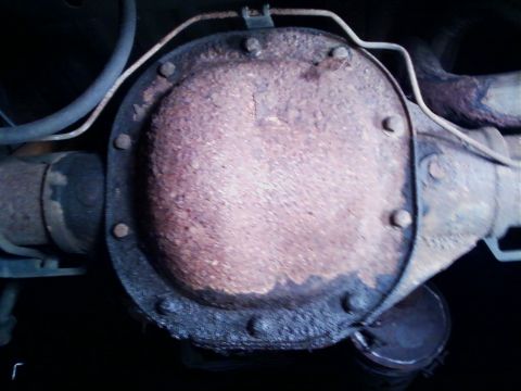1990 Ford Bronco - Close-up view of a heavily rusted differential housing and attached exhaust pipe.