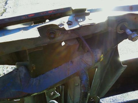 1990 Ford Bronco - Close-up of rusted vehicle frame and suspension components under bright sunlight.