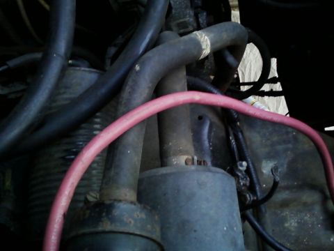 1990 Ford Bronco - Close-up view of engine components including hoses and a starter motor.