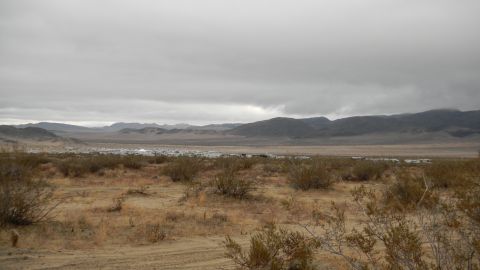 1997 Ford Ranger - A wide shot of a desert landscape shows sparse vegetation in the foreground and distant vehicles under a cloudy sky.