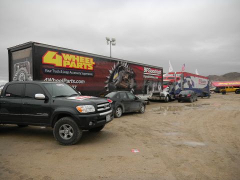 1997 Ford Ranger - A black Toyota Tundra pickup truck is parked in a dirt lot with several large trailers in the background.