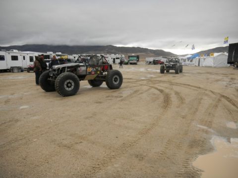 1997 Ford Ranger - Multiple off-road vehicles and RVs are gathered in a dusty, outdoor event area under a cloudy sky.