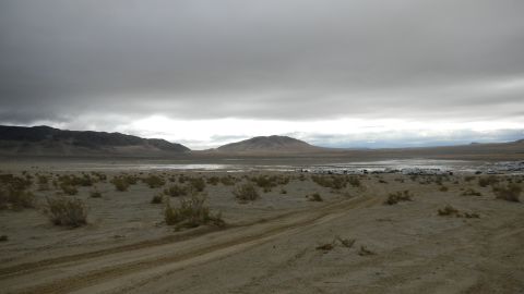 1997 Ford Ranger - A wide desert landscape stretches out under a dramatic, cloudy sky, with a line of vehicles visible in the far distance.