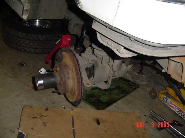Front disc brake rotor and hub exposed with wheel removed, vehicle on jack stand