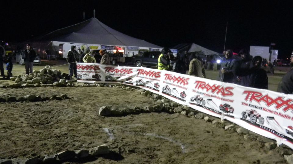 Traxxas banner stretched across a dirt track at night with people and tents in the background