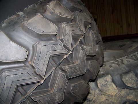 2001 Dodge 1500 - A close-up view of a damaged tire, showing a large gash across its aggressive tread pattern.