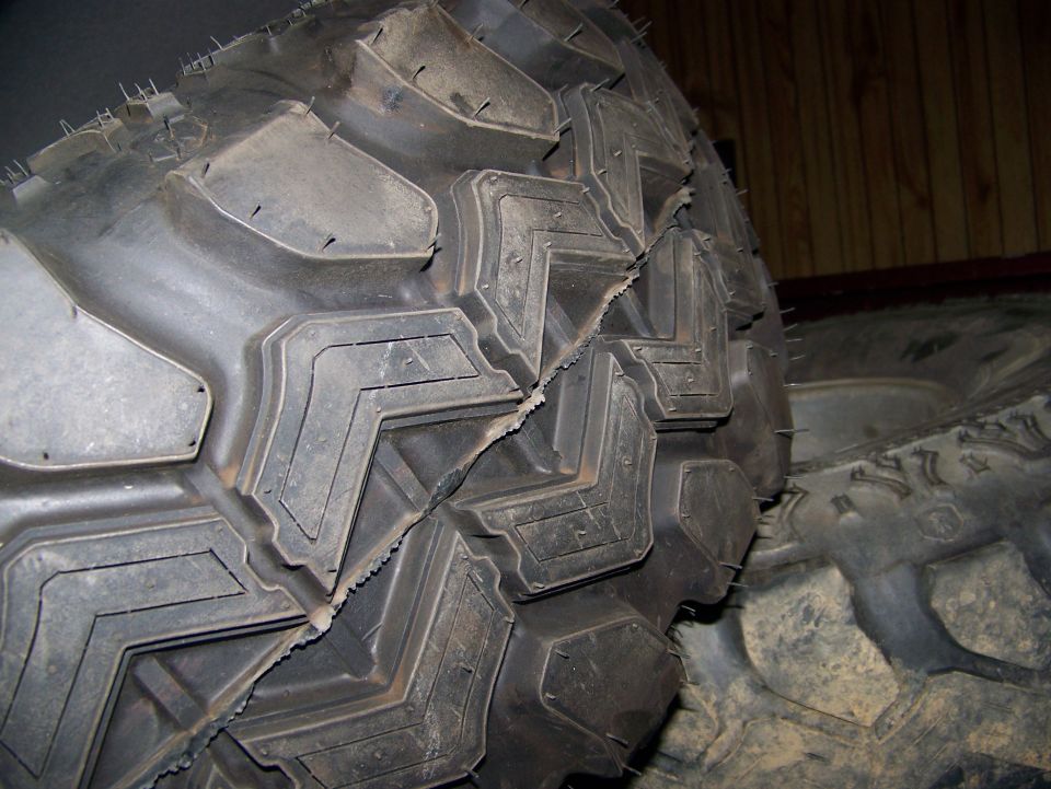 Close-up of a large, off-road tire with a significant tear in the tread