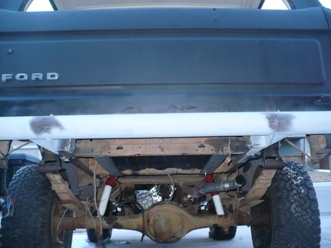 1979 Ford Bronco - The underside of a Ford truck is visible, focusing on the rear axle and suspension components.