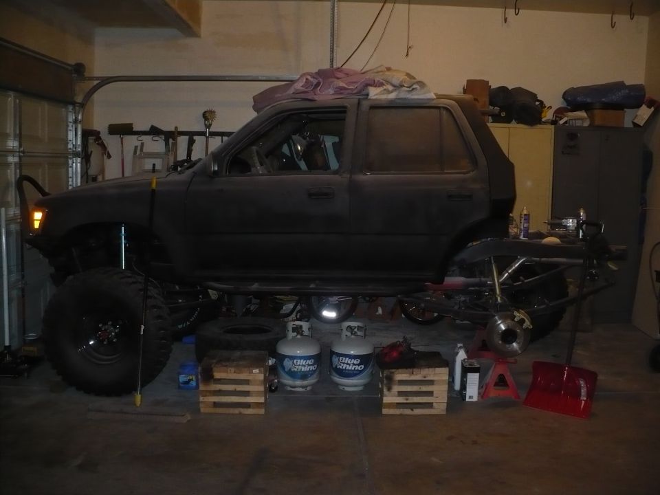 Dark-colored SUV lifted on blocks with exposed suspension and drivetrain components