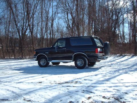 1989 Ford Bronco - A black 1989 Ford Bronco is seen from the side, parked in a snowy, wooded area.