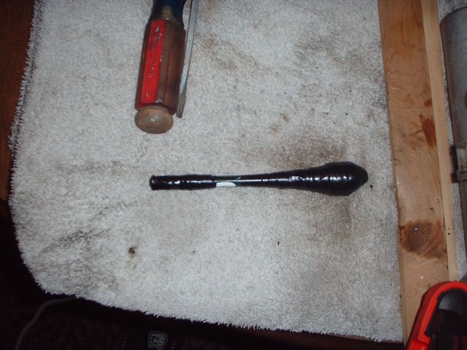 Black electrical-tape-wrapped part on a dirty towel beside a red-handled chisel