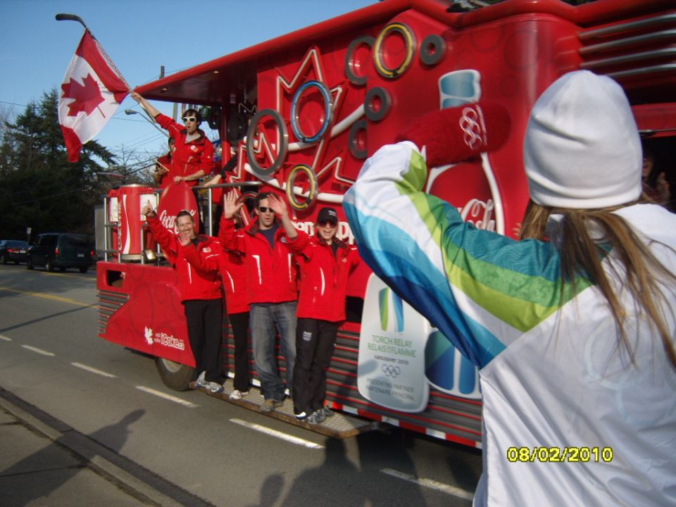 Red Coca-Cola Olympic torch relay float with people waving Canadian flag