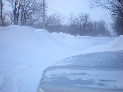 1978 Ford Bronco - A vehicle navigates a snow-covered road, with deep snowdrifts lining the path and trees visible in the background.