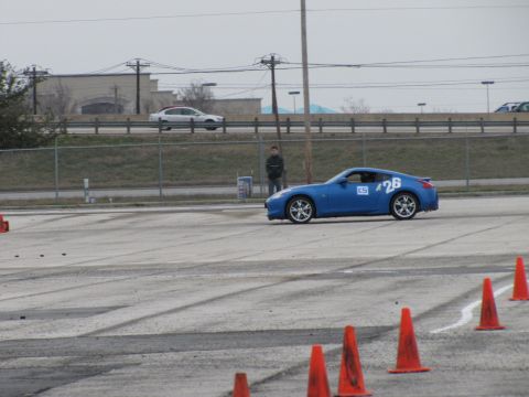 2003 Mazda Protege - A blue sports car navigates a course marked by orange cones, with a spectator in the background.