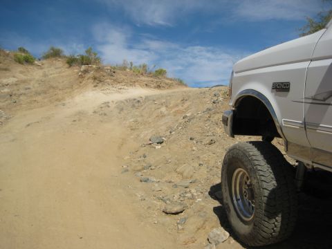 1996 Ford Bronco - Off-roading in a 1996 Ford Bronco on a dusty, rocky trail under a blue sky.