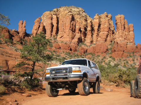 1996 Ford Bronco - White Ford Bronco parked in front of red rock formations, with another vehicle partially visible.
