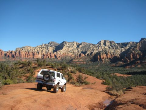 1996 Ford Bronco - A white 1996 Ford Bronco is parked on a rocky trail, with a scenic mountain range under a clear blue sky.