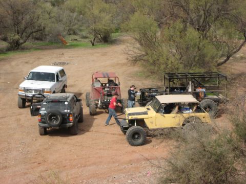 1996 Ford Bronco - A white SUV is parked in a dusty, outdoor area with several other off-road vehicles.