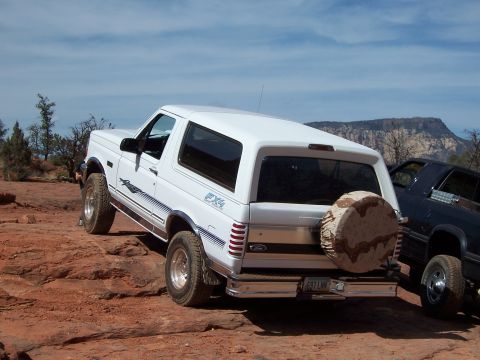 1996 Ford Bronco - A white 1996 Ford Bronco is parked on a rocky, red dirt terrain with another vehicle nearby.
