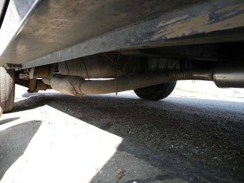 1993 Dodge Grand Caravan - The underside of a vehicle reveals its exhaust system and fuel tank, with a tire visible on the left.
