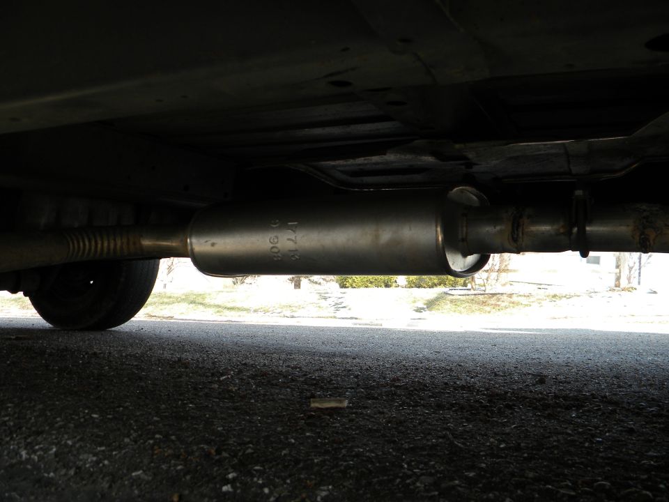 Underbody view of newly installed oval exhaust muffler with clamped tailpipe and flex pipe