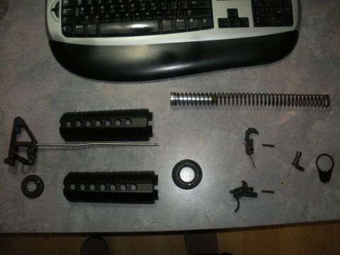 1996 Ford Bronco - Various parts of a disassembled rifle are laid out on a surface next to a keyboard.