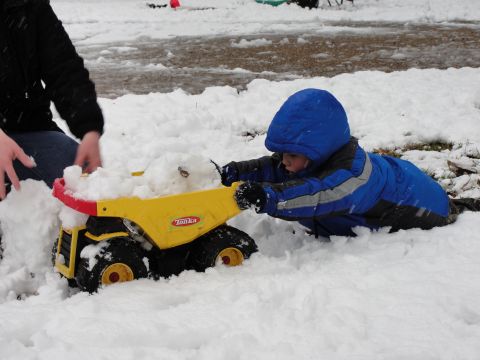 1967 Ford Mustang - Child plays with a toy dump truck in the snow, with a person in the background.